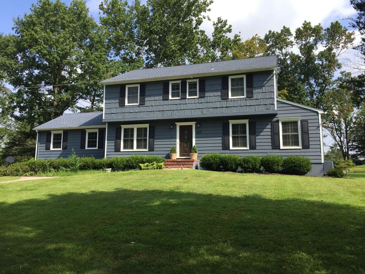 A blue-grey two-storey colonial after new siding and trim